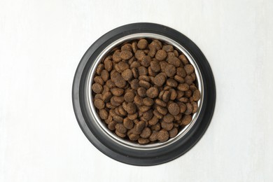 Photo of Dry pet food in feeding bowl on light background, top view