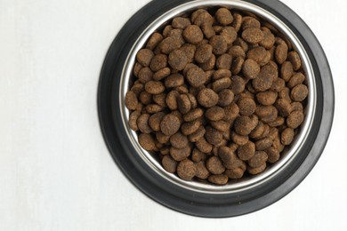 Photo of Dry pet food in feeding bowl on light background, top view