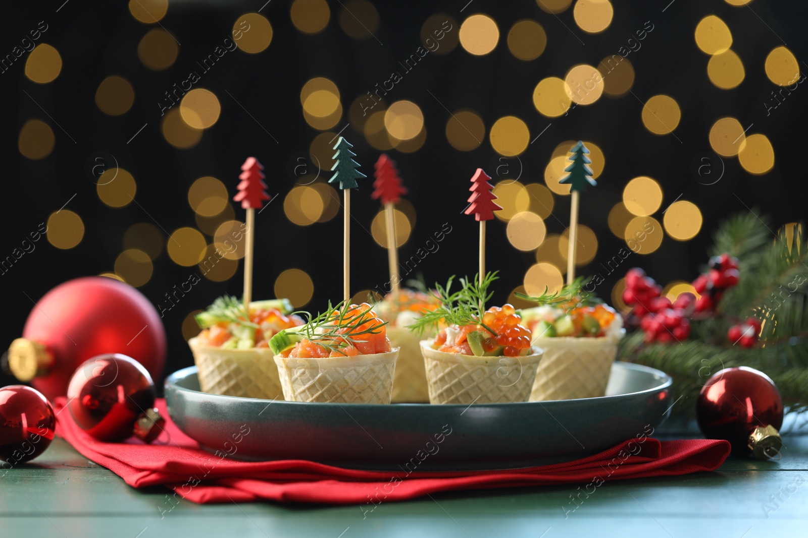 Tasty canapes and Christmas decor on green wooden table against black background with blurred lights, closeup. Bokeh effect Photo of Tasty canapes and Christmas decor on green wooden table against black background with blurred lights, closeup. Bokeh effect