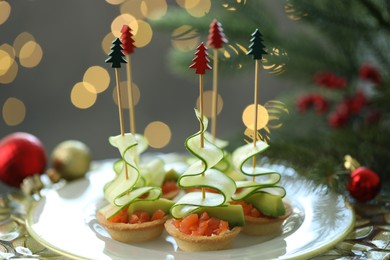 Photo of Tasty canapes and Christmas decor on table against background with blurred lights, closeup. Bokeh effect