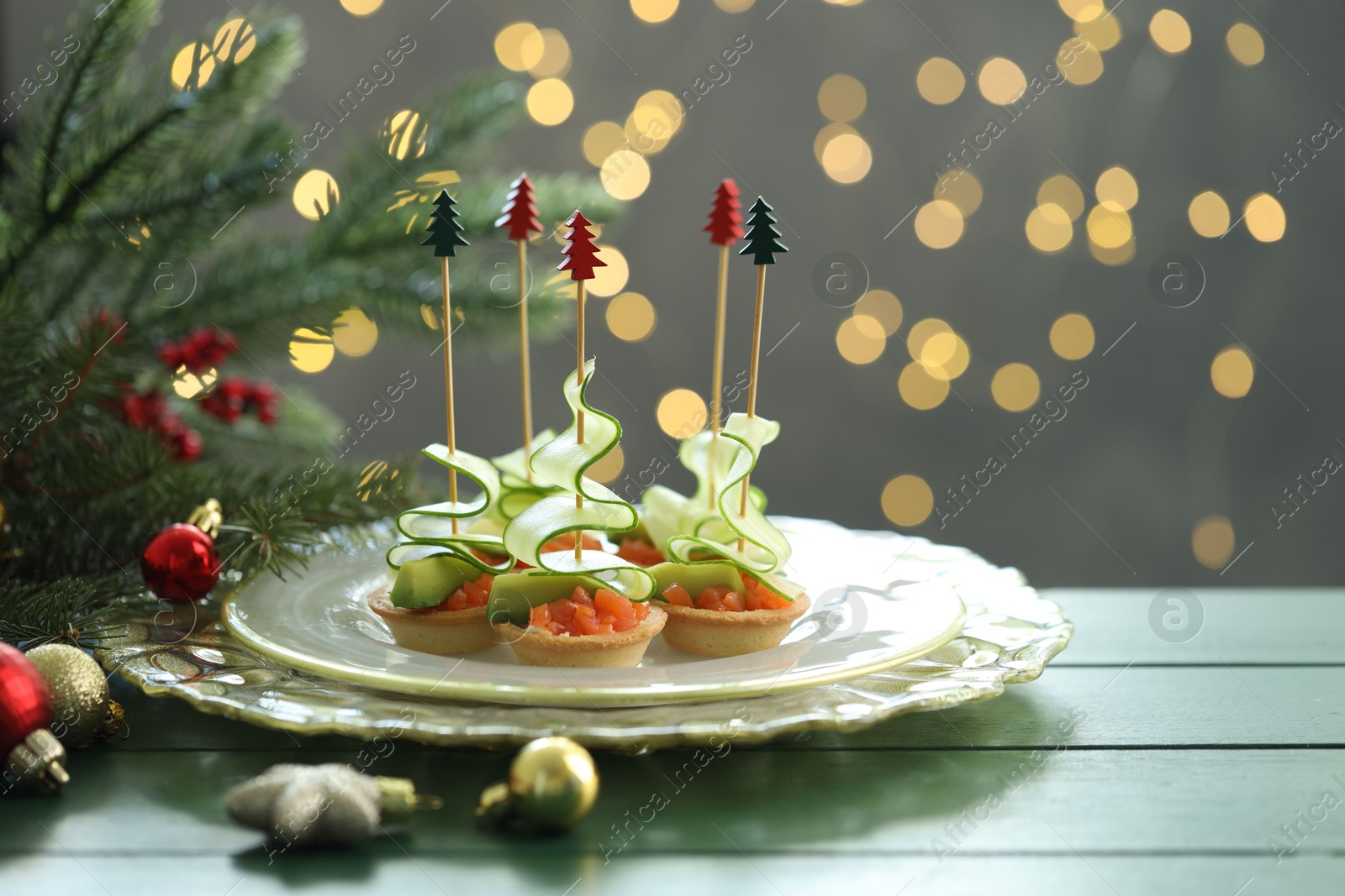 Tasty canapes and Christmas decor on green wooden table against background with blurred lights, space for text. Bokeh effect Photo of Tasty canapes and Christmas decor on green wooden table against background with blurred lights, space for text. Bokeh effect
