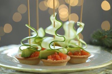 Photo of Tasty canapes and Christmas decor on table against background with blurred lights, closeup. Bokeh effect
