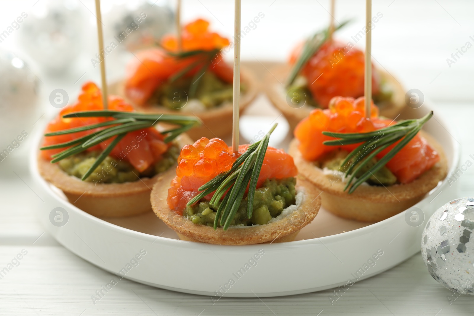 Photo of Tasty canapes and Christmas decor on white wooden table, closeup