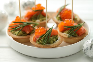 Photo of Tasty canapes and Christmas decor on white wooden table, closeup