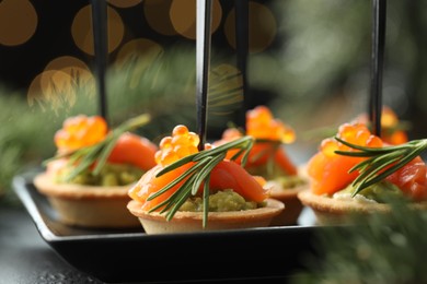 Photo of Tasty canapes and Christmas decor on table, closeup. Bokeh effect
