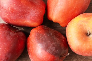 Photo of Many rotten red apples on wooden table, closeup