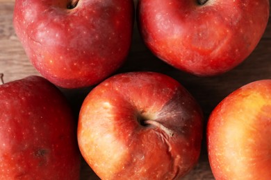 Photo of Many rotten red apples on wooden table, closeup
