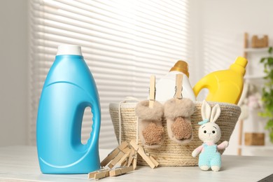 Photo of Bottles with fabric softeners, clothespins and toy on light wooden table indoors