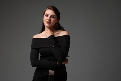 Photo of Young woman in stylish black dress on grey background
