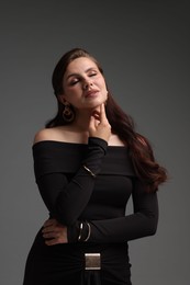 Photo of Young woman in stylish black dress on grey background
