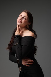 Photo of Young woman in stylish black dress on grey background