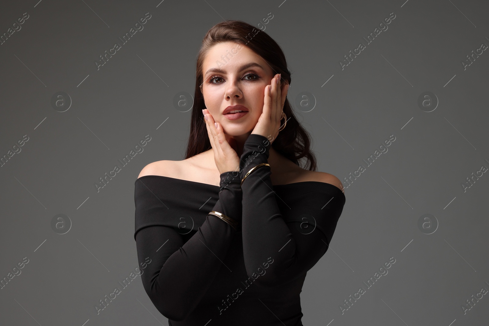Young woman in stylish black dress on grey background Photo of Young woman in stylish black dress on grey background