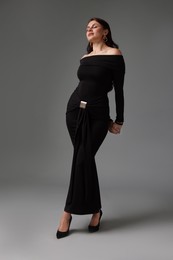 Photo of Young woman in stylish black dress on grey background