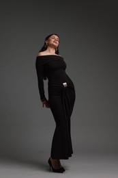 Photo of Young woman in stylish black dress on grey background