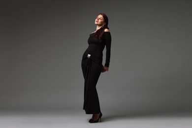 Photo of Young woman in stylish black dress on grey background