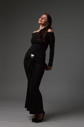Photo of Young woman in stylish black dress on grey background