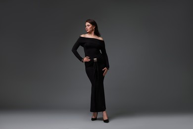 Photo of Young woman in stylish black dress on grey background