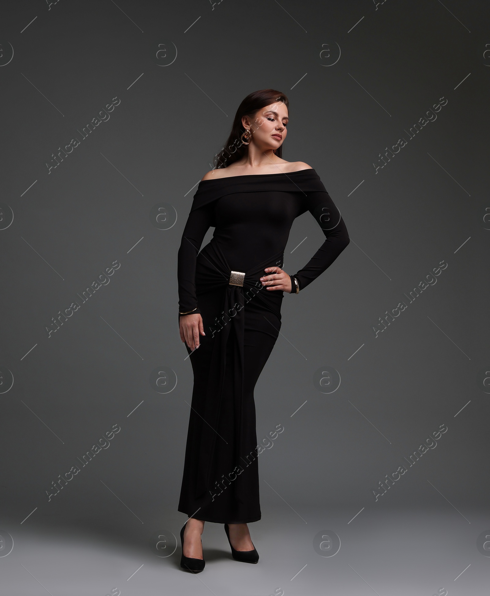 Young woman in stylish black dress on grey background Photo of Young woman in stylish black dress on grey background
