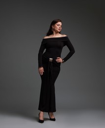 Photo of Young woman in stylish black dress on grey background