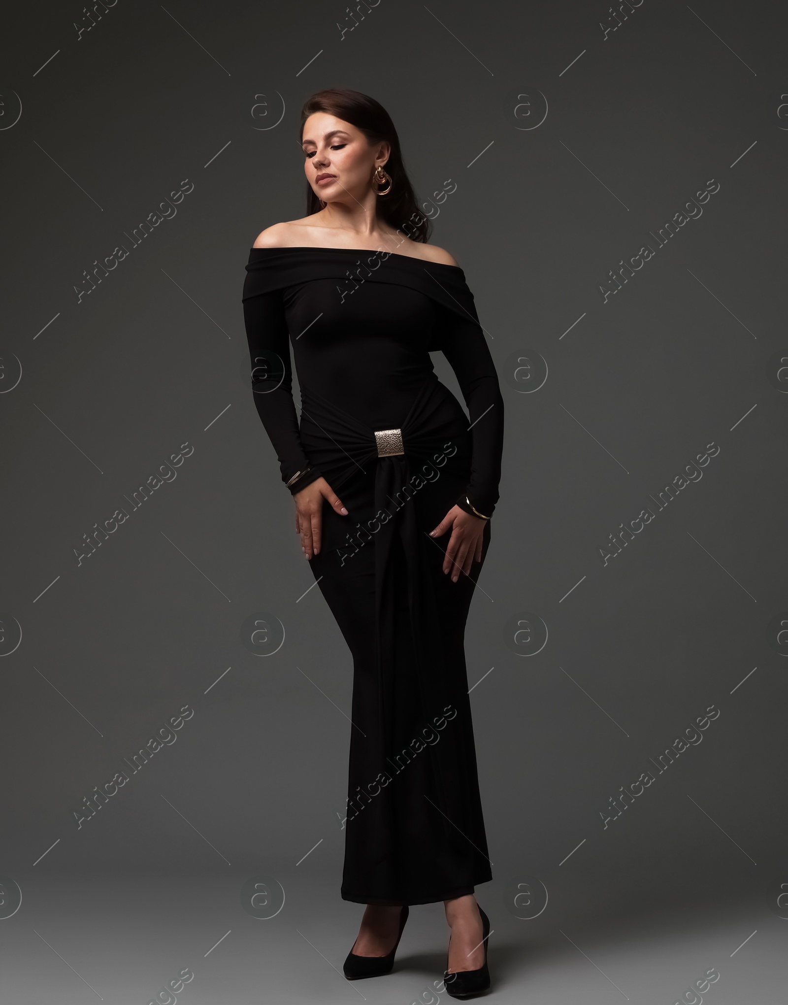 Young woman in stylish black dress on grey background Photo of Young woman in stylish black dress on grey background