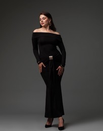 Photo of Young woman in stylish black dress on grey background