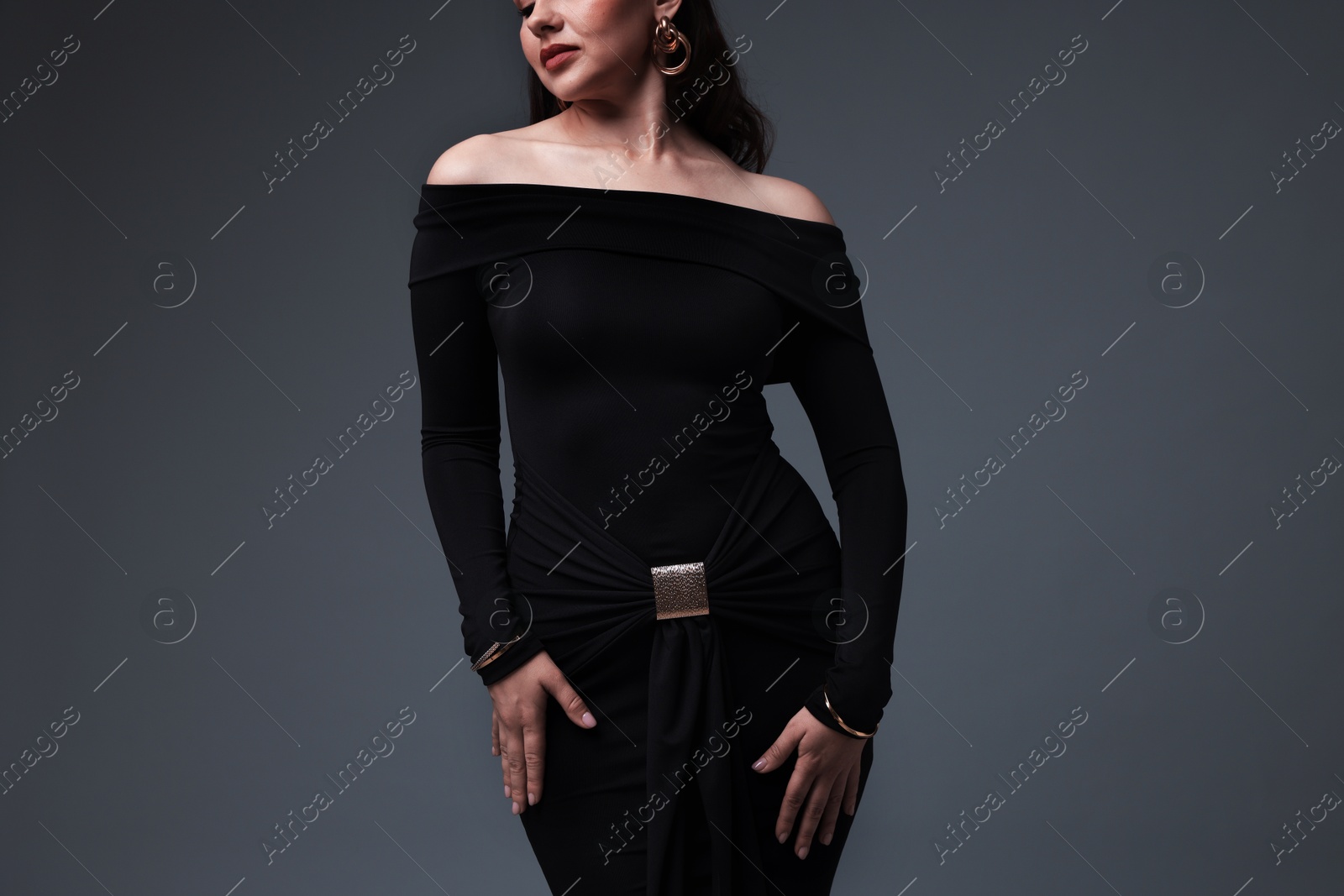 Young woman in stylish black dress on grey background, closeup Photo of Young woman in stylish black dress on grey background, closeup