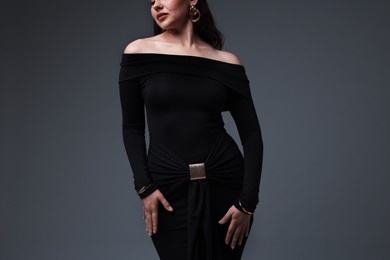 Photo of Young woman in stylish black dress on grey background, closeup