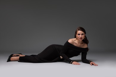 Photo of Young woman in stylish black dress on grey background