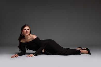 Photo of Young woman in stylish black dress on grey background