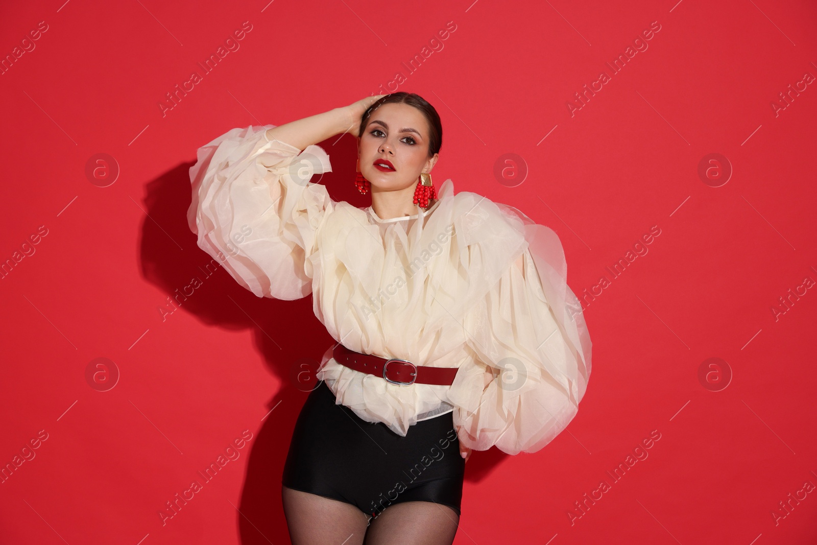 Young woman in stylish clothes on red background Photo of Young woman in stylish clothes on red background