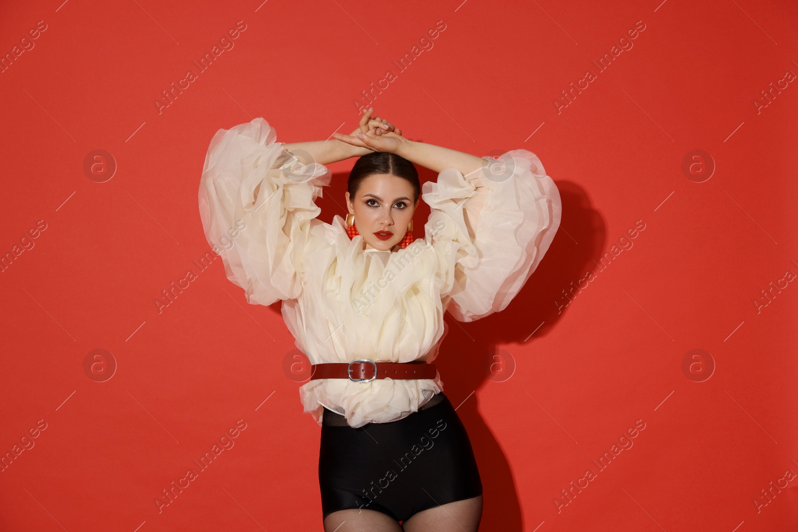 Young woman in stylish clothes on red background Photo of Young woman in stylish clothes on red background
