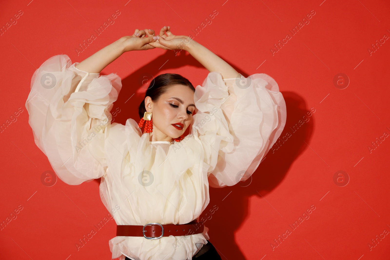Young woman in stylish clothes on red background Photo of Young woman in stylish clothes on red background