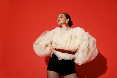 Photo of Young woman in stylish clothes on red background