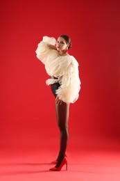 Photo of Young woman in stylish clothes on red background