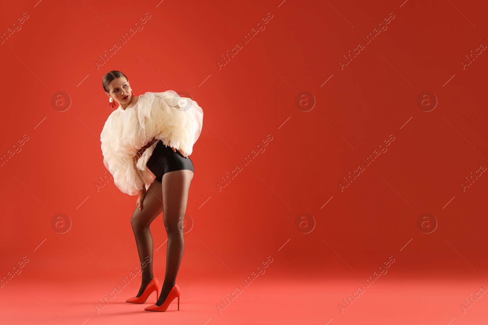 Young woman in stylish clothes on red background, space for text Photo of Young woman in stylish clothes on red background, space for text