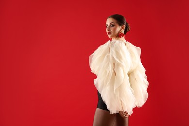 Photo of Young woman in stylish clothes on red background, space for text