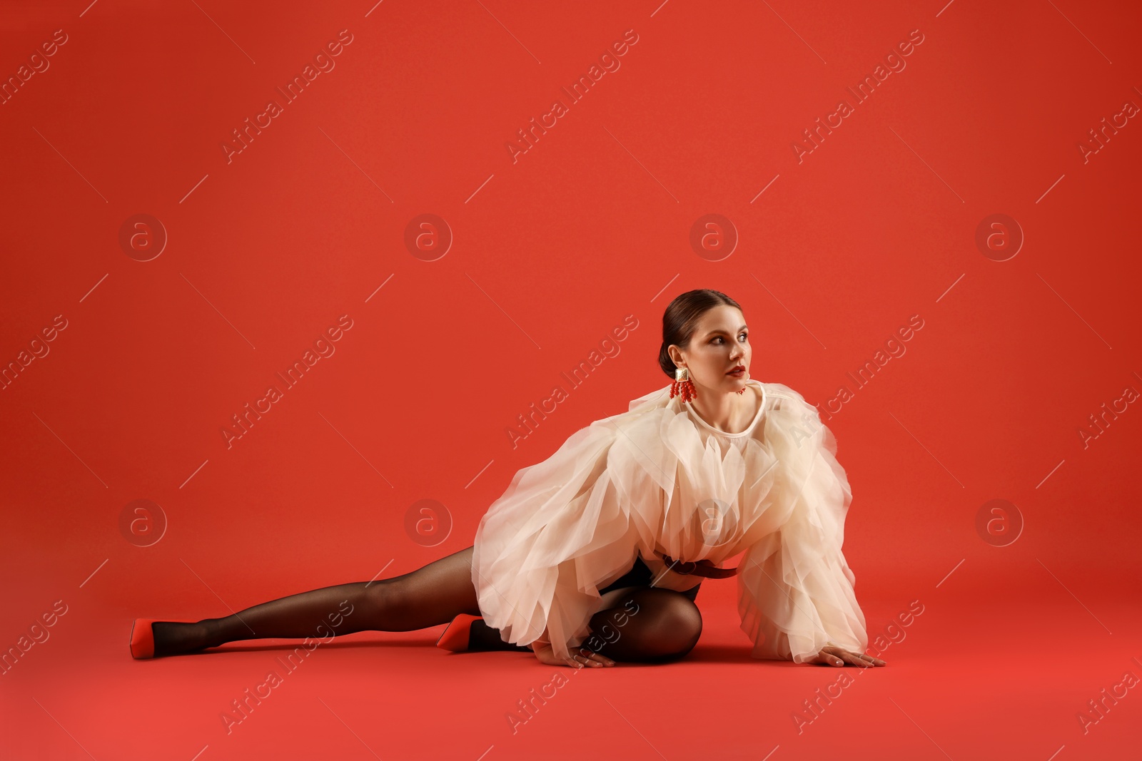 Young woman in stylish clothes on red background Photo of Young woman in stylish clothes on red background