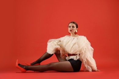 Photo of Young woman in stylish clothes on red background