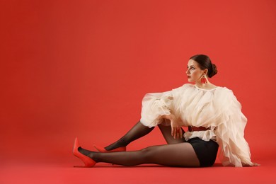 Photo of Young woman in stylish clothes on red background, space for text