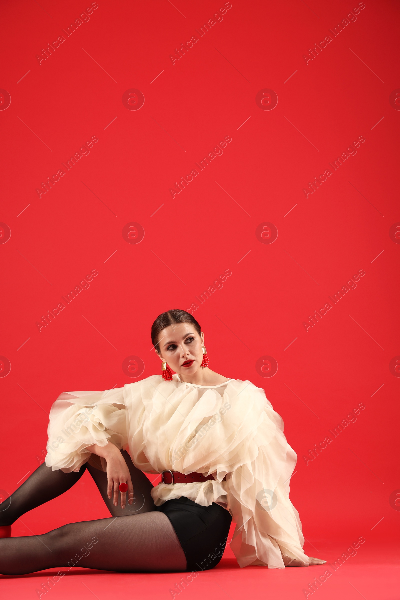 Young woman in stylish clothes on red background, space for text Photo of Young woman in stylish clothes on red background, space for text
