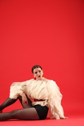 Photo of Young woman in stylish clothes on red background, space for text