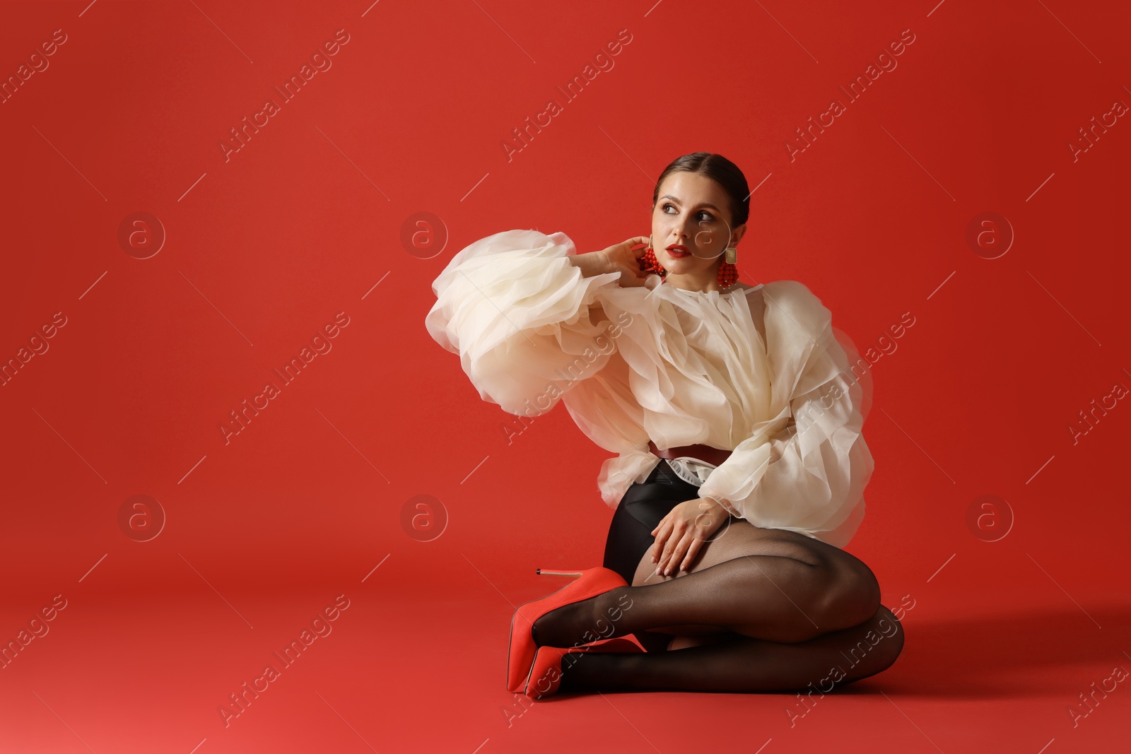 Young woman in stylish clothes on red background, space for text Photo of Young woman in stylish clothes on red background, space for text