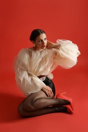 Photo of Young woman in stylish clothes on red background