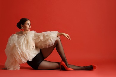 Photo of Young woman in stylish clothes on red background, space for text