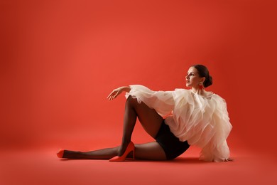 Photo of Young woman in stylish clothes on red background, space for text