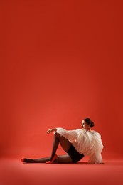 Photo of Young woman in stylish clothes on red background, space for text