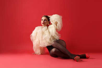 Photo of Young woman in stylish clothes on red background