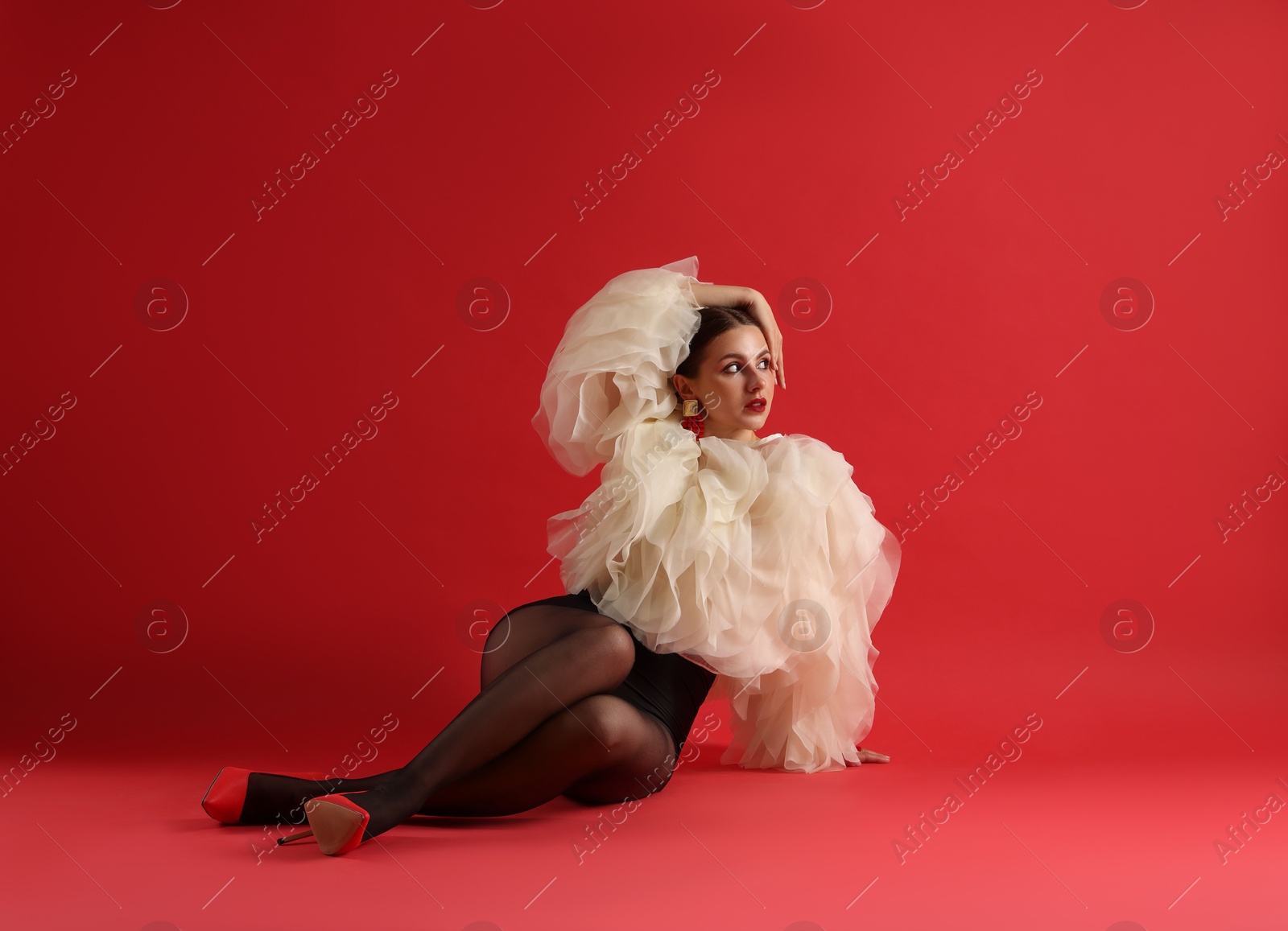 Young woman in stylish clothes on red background Photo of Young woman in stylish clothes on red background