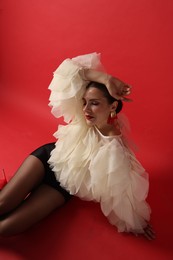 Photo of Young woman in stylish clothes on red background