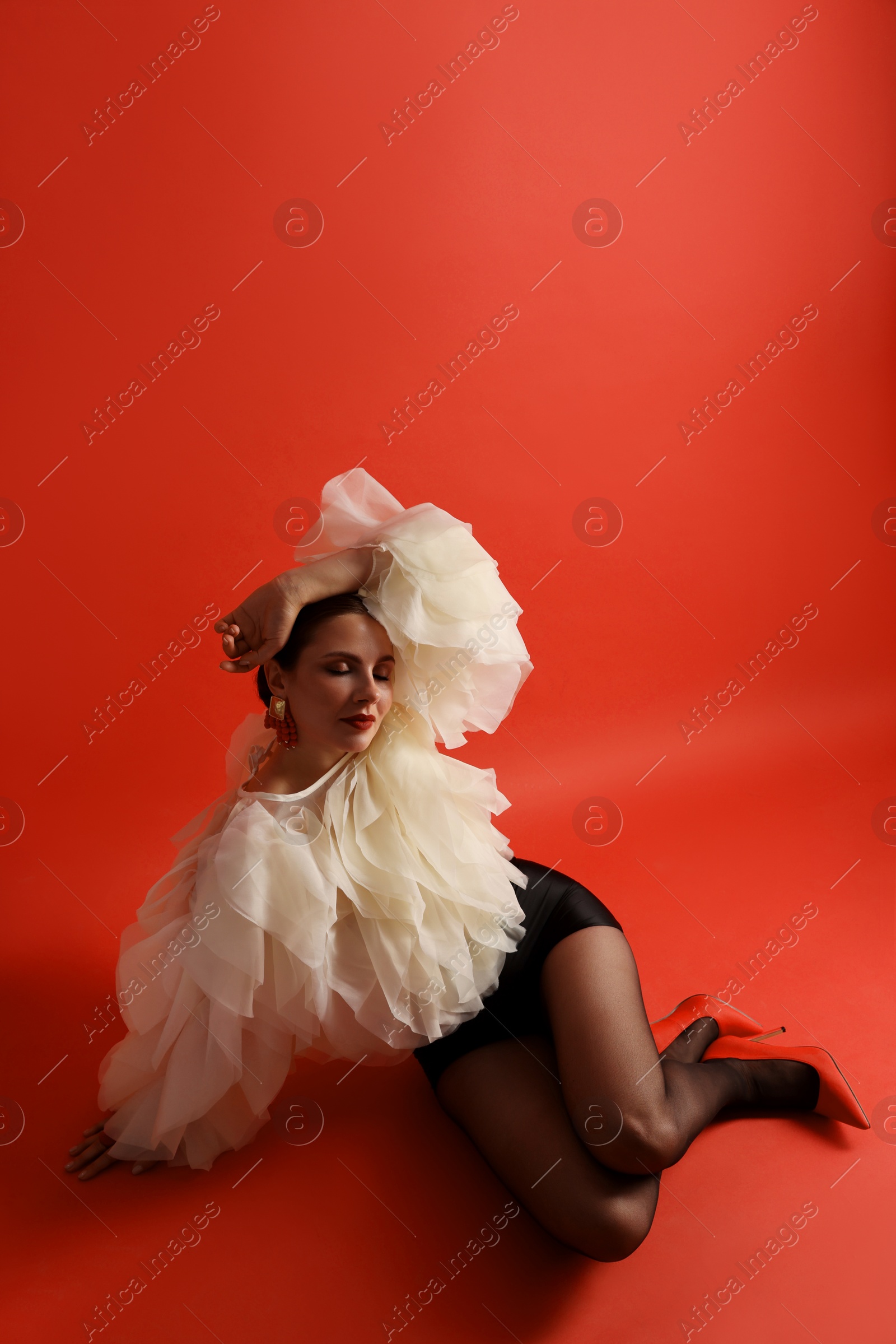 Young woman in stylish clothes on red background Photo of Young woman in stylish clothes on red background